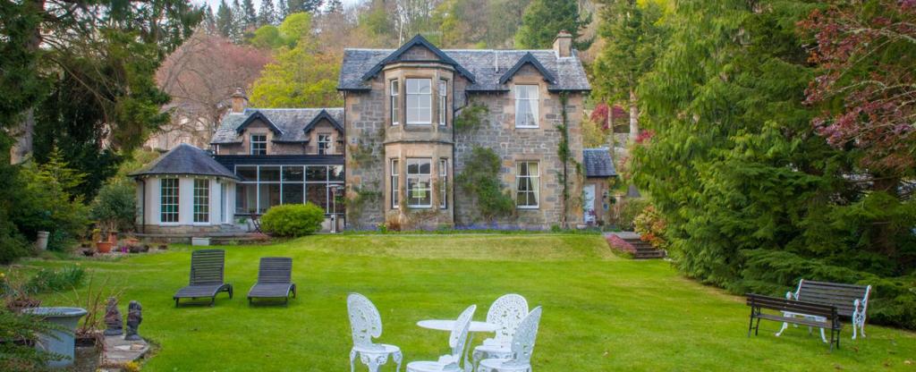 a large house with chairs and a table in the yard at Lubnaig Guest House in Callander