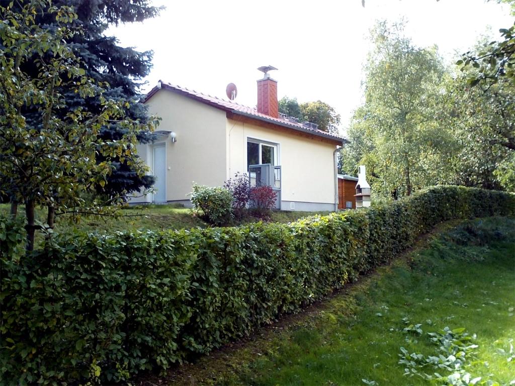a white house with a hedge in front of it at Ferienhaus zur Blautanne in Klipphausen
