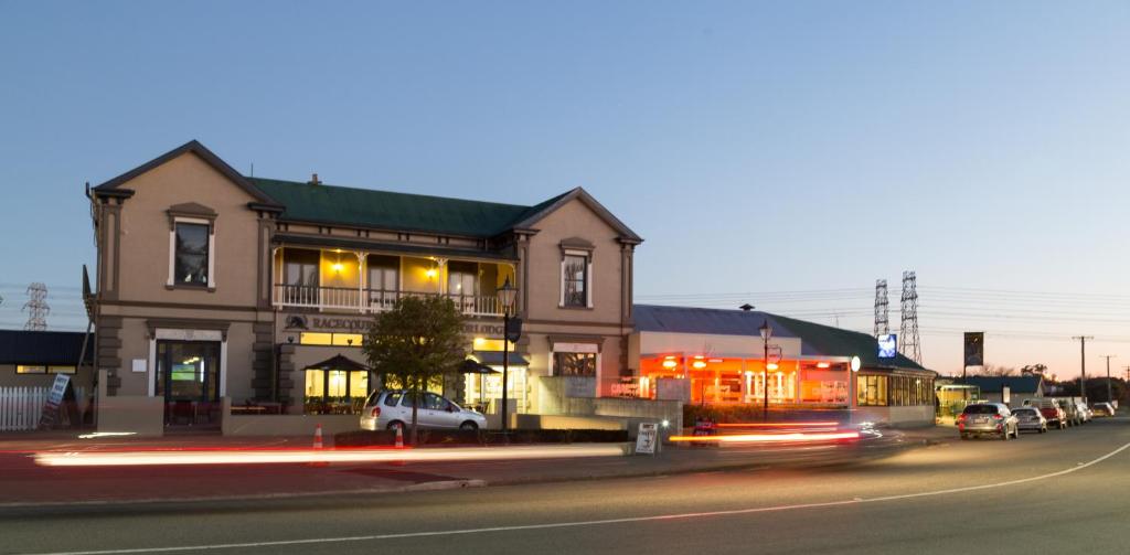 基督城的住宿－Racecourse Hotel and Motor Lodge，街道上的建筑物,前面有车辆停放