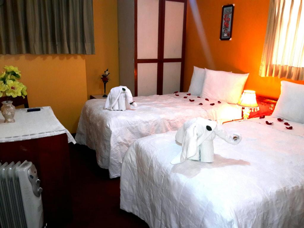 Ayma Hostel Puno في بونو: سريرين في غرفة الفندق عليها فيلة