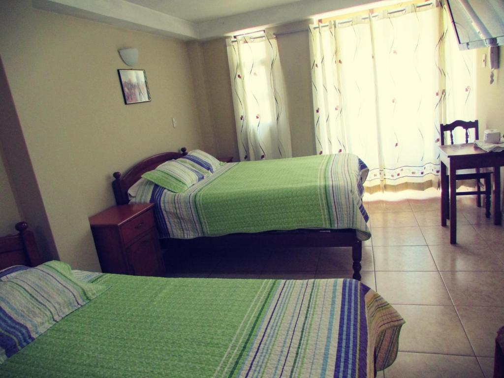 a bedroom with two beds and a table and a window at El Balcon Hostal in Ayacucho