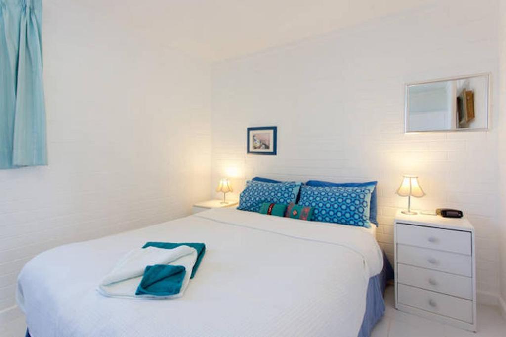 a bedroom with a large white bed with blue pillows at Ocean Harbour Views in Fremantle