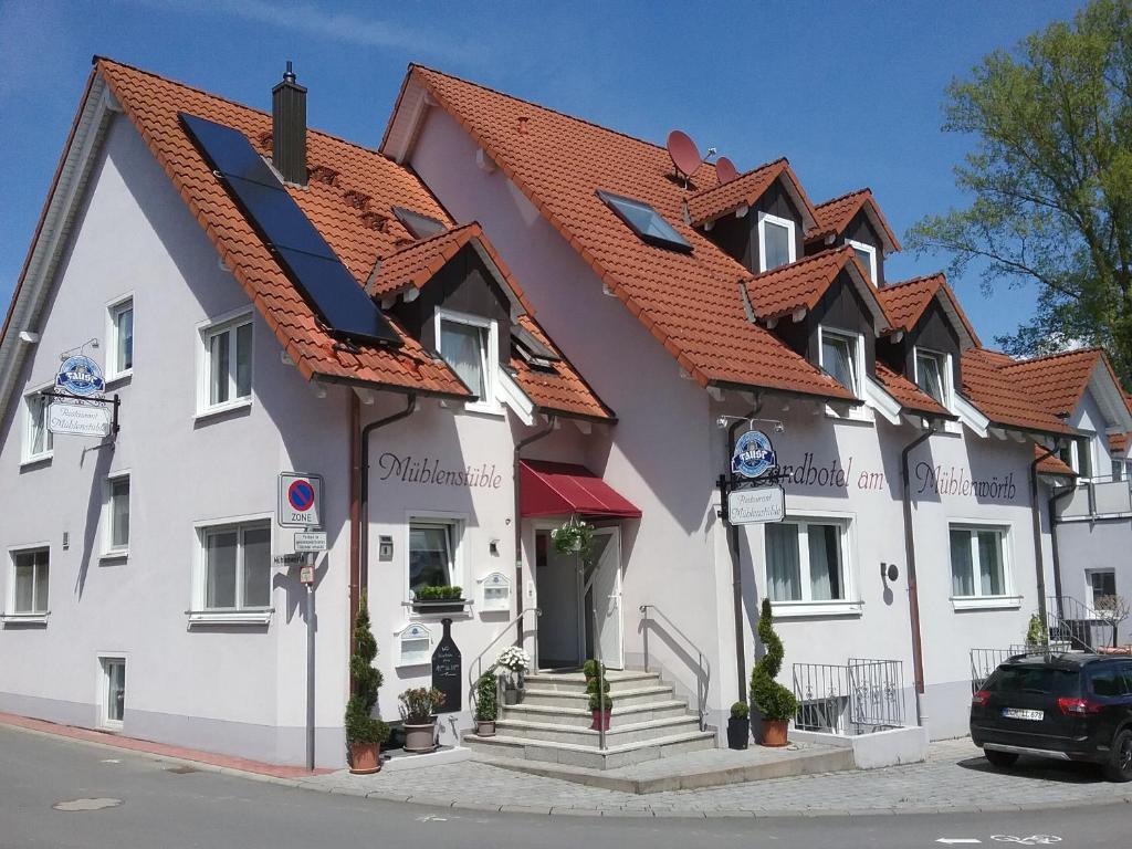 un grand bâtiment blanc avec un toit rouge dans l'établissement Landhotel Garni am Mühlenwörth, à Tauberbischofsheim