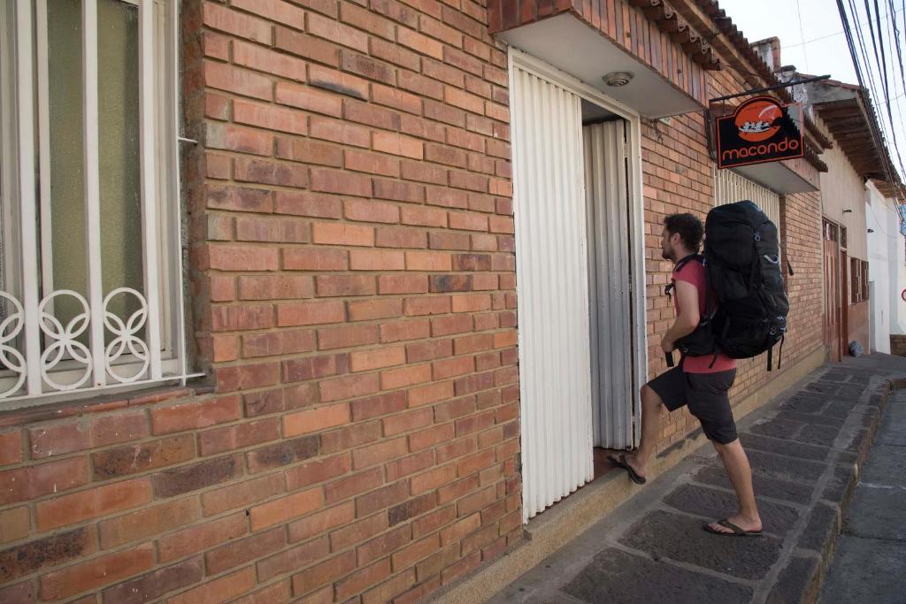 a woman with a backpack standing outside of a building at Macondo Hostel in San Gil