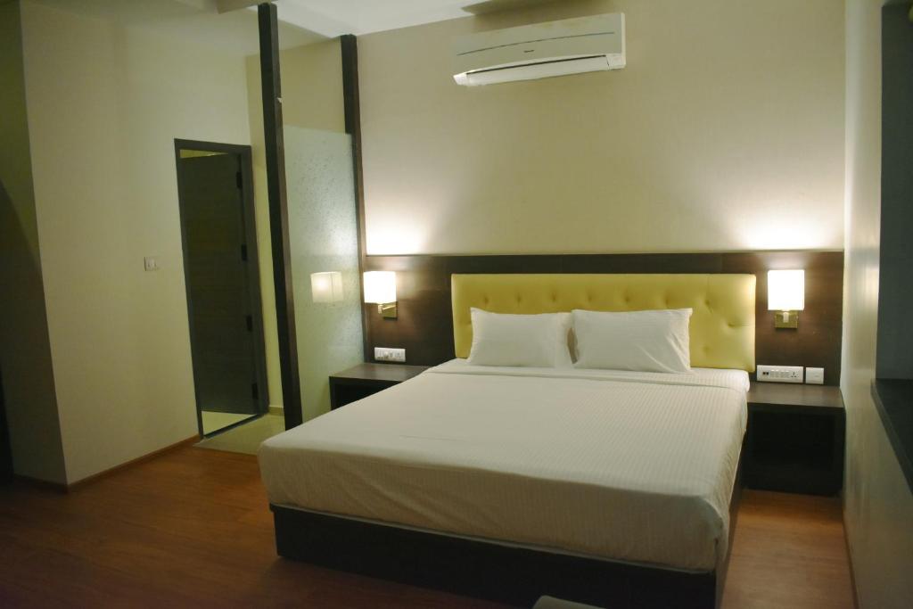 1 dormitorio con 1 cama grande con sábanas y almohadas blancas en Grand Arcadia, en Tiruchchirāppalli