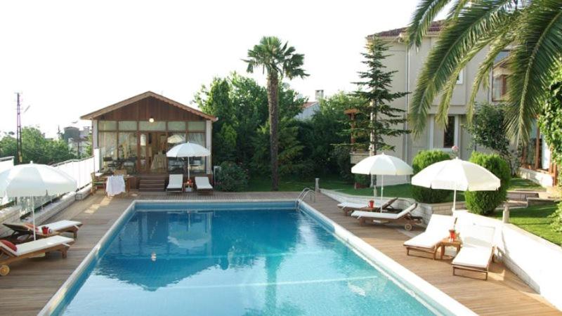 a swimming pool with chairs and umbrellas next to a house at Parla Viens Suites in Gebze