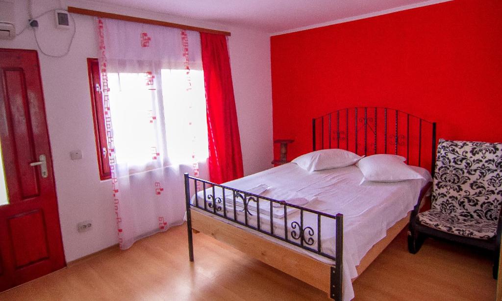 1 dormitorio con paredes rojas, 1 cama y 1 silla en Camere de închiriat Doriana, en Vama Veche