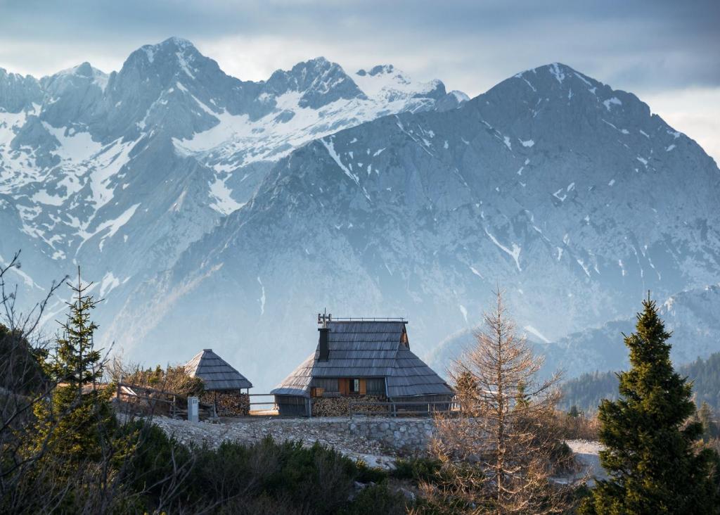 una grande montagna innevata di fronte a una casa di Koča Ojstrica - Velika planina a Stahovica