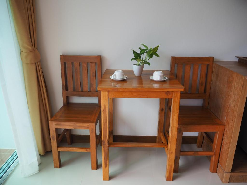 a wooden table and two chairs with a plant on it at Crystal Lamai Hotel in Lamai