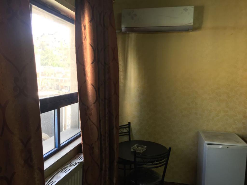 اسيا اوتيل في عمّان: غرفة صغيرة بها نافذة وطاولة وكرسي