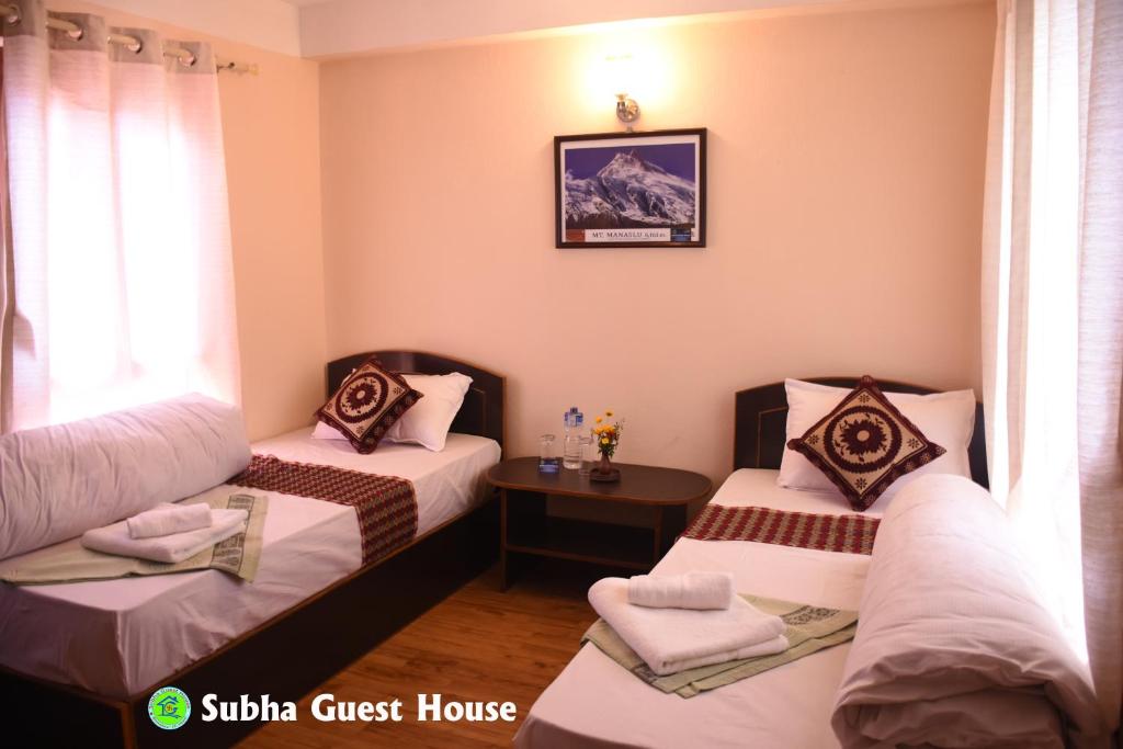 a hotel room with two beds and a table at Subha Guest House in Bhaktapur