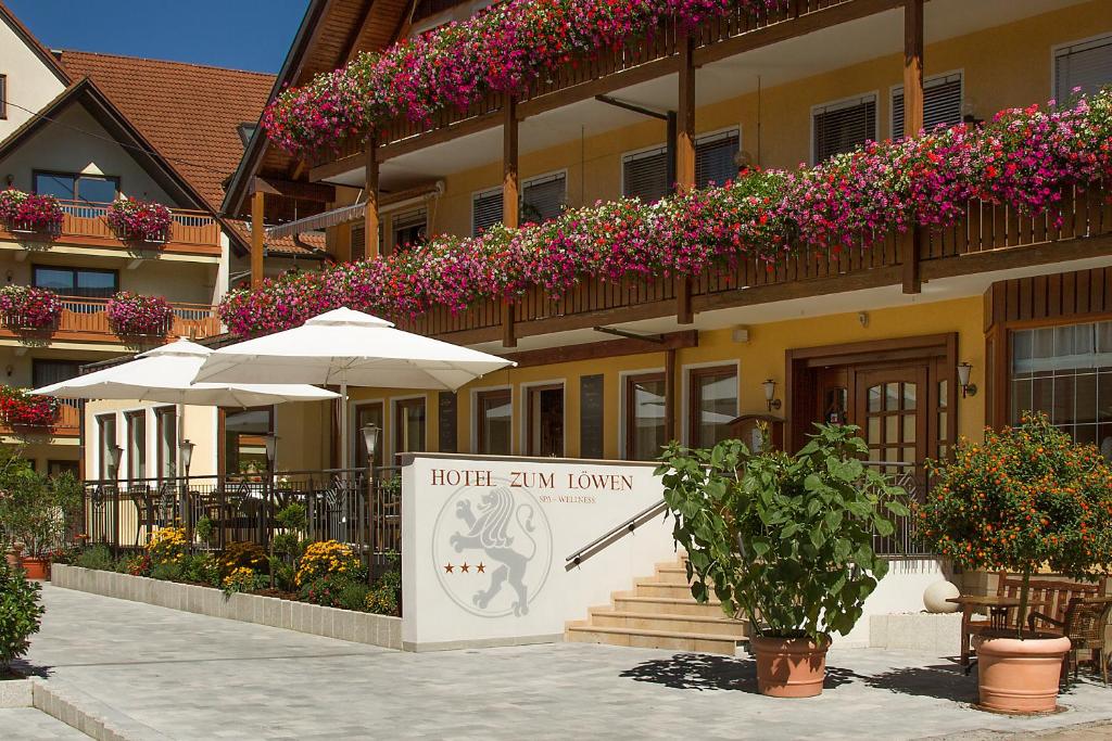 a hotel with a sign in front of a building with flowers at Gasthof - Hotel Zum Löwen in Schwabthal
