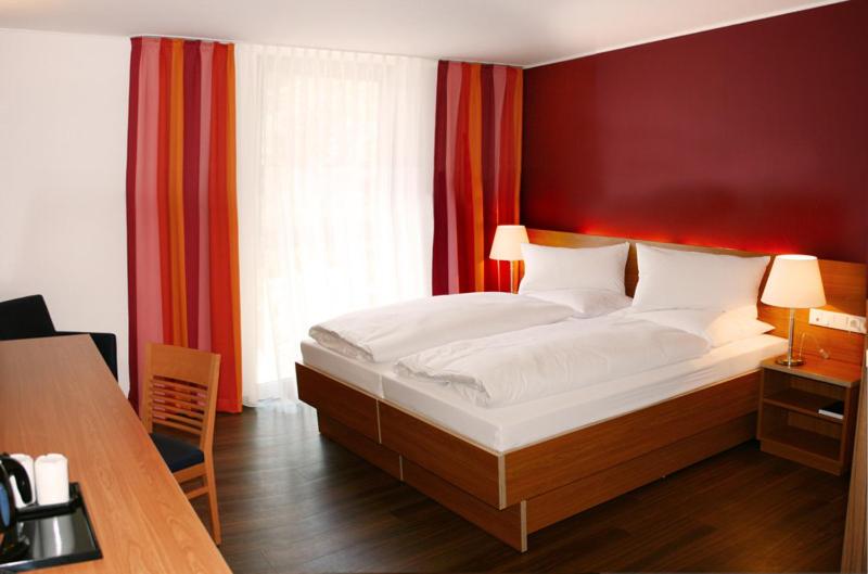 a bedroom with a large bed with red walls at Hotel Franz in Essen