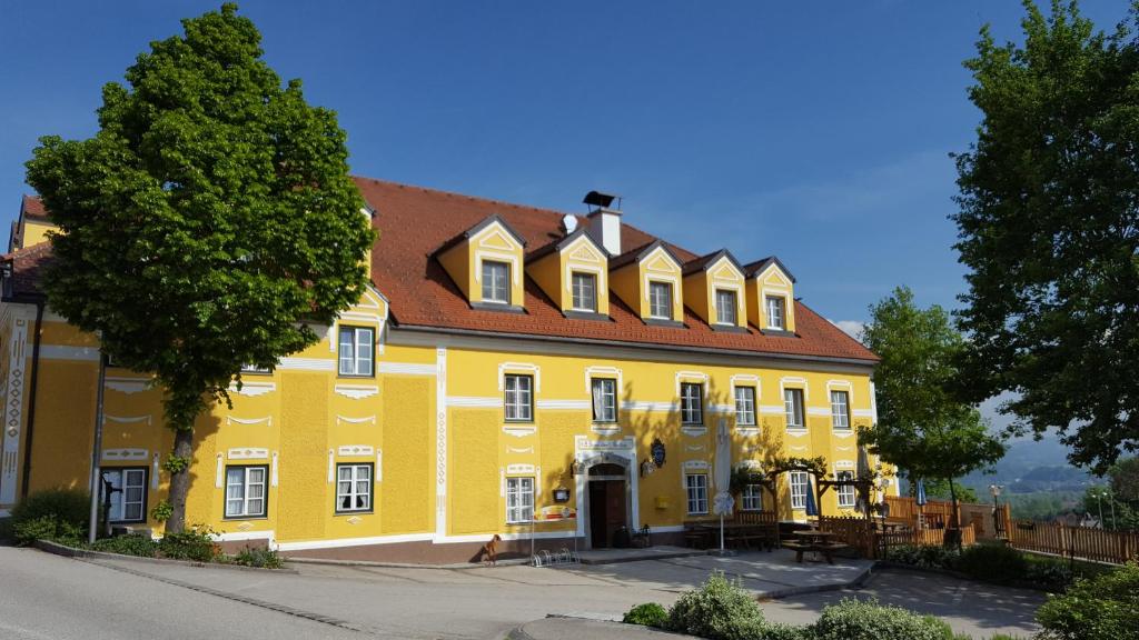 ein großes gelbes Gebäude mit rotem Dach in der Unterkunft Gasthof Kremslehner in Stephanshart