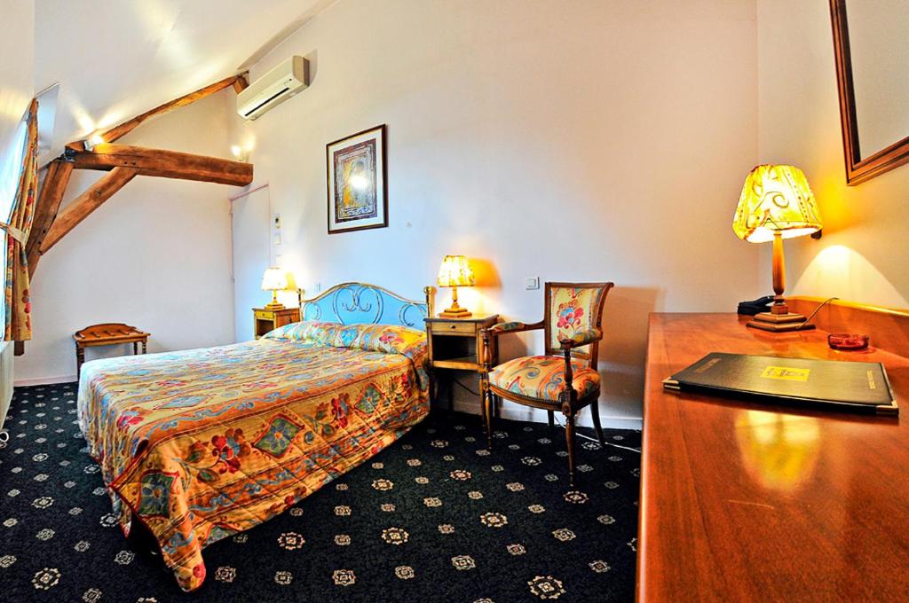 a hotel room with a bed and a desk and a bed sidx sidx at Le Grand Monarque in La Charité-sur-Loire