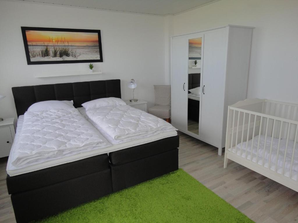 a bedroom with a bed and a crib at Fewo Am Deich mit Garten, 70m zum Strand, Fahrradgarage in Dahme