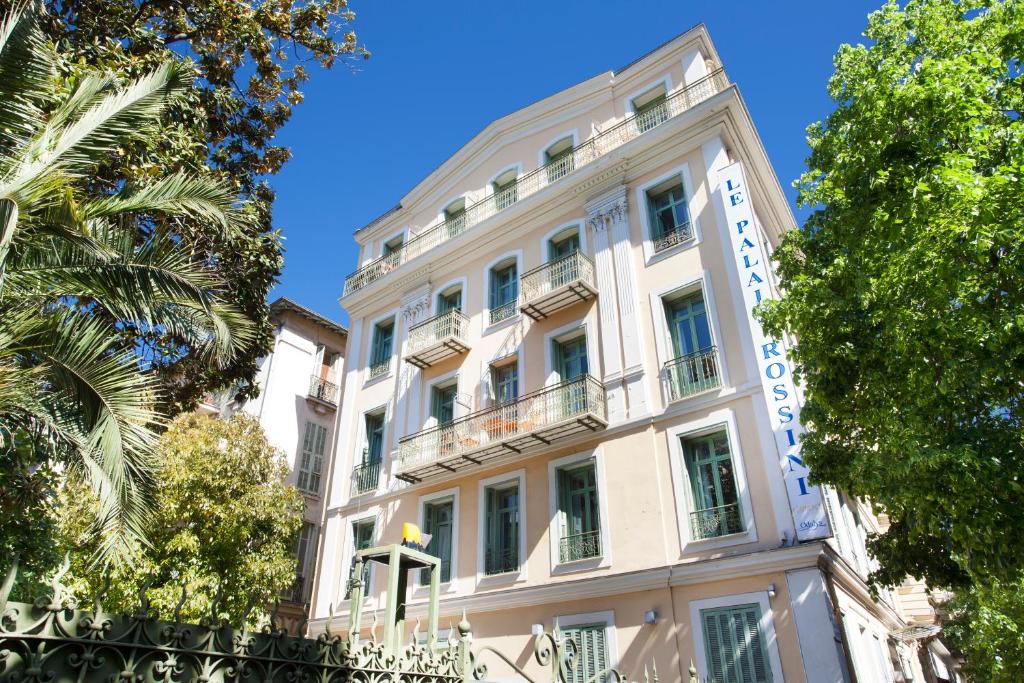 un grand bâtiment blanc avec des arbres devant lui dans l'établissement Odalys City Nice Le Palais Rossini, à Nice