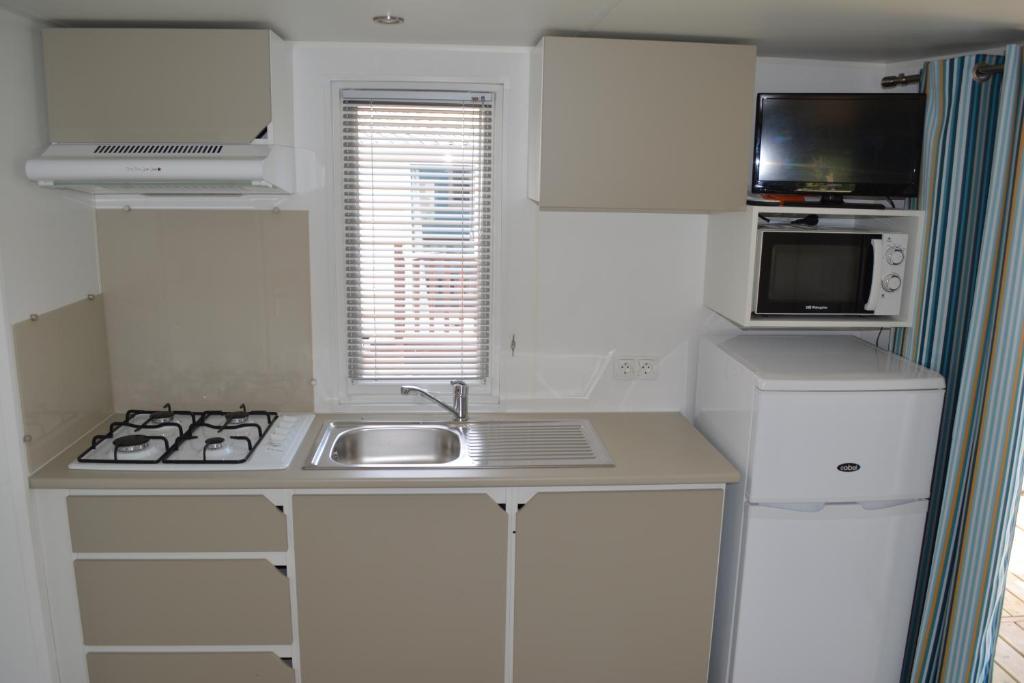 a small kitchen with a sink and a microwave at Camping Valencia el Saler in El Saler