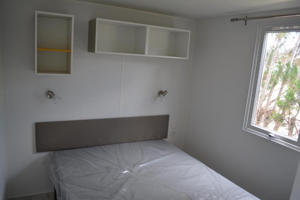 a bed in a room with a white wall at Camping Valencia el Saler in El Saler