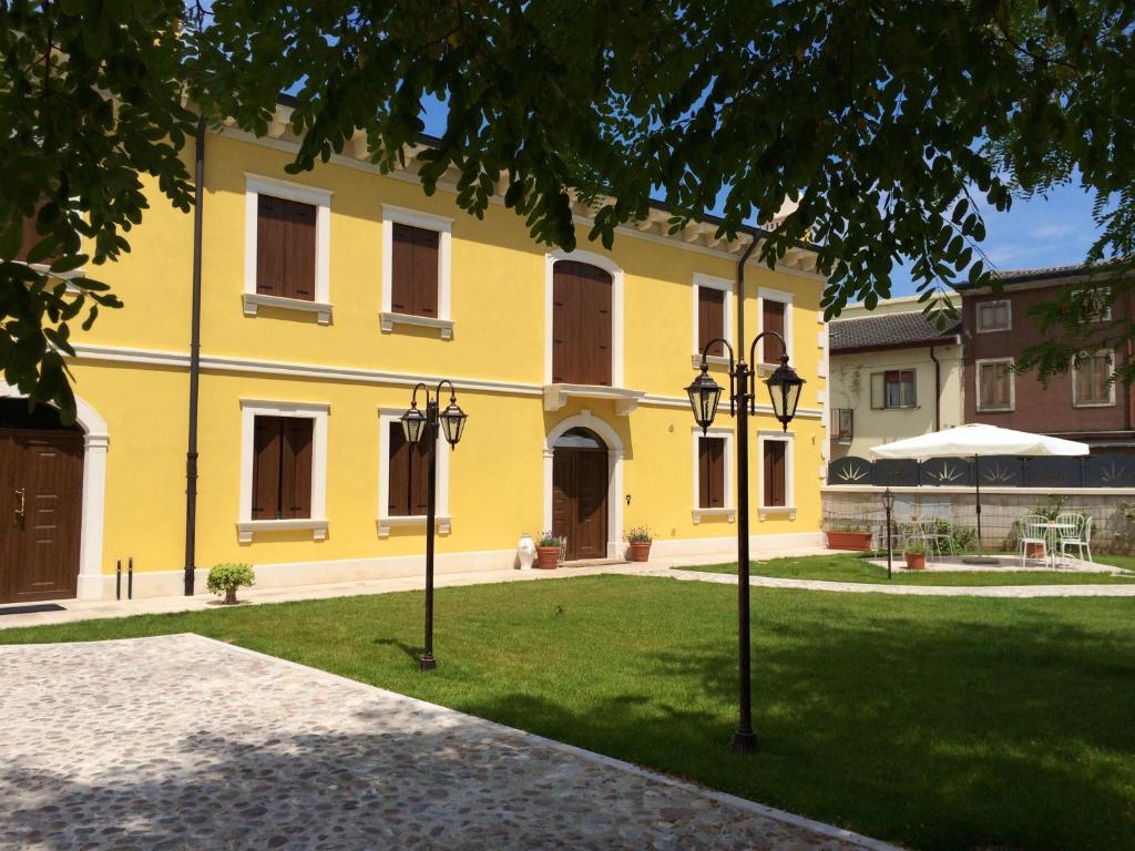 a yellow building with two street lights in the grass at Il Conte in San Bonifacio
