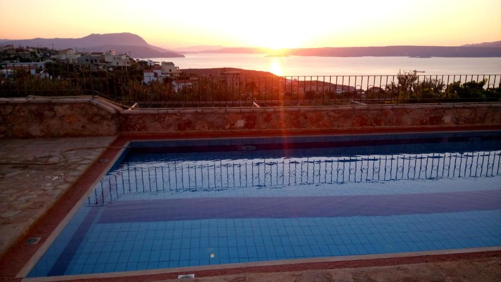 a swimming pool with the sunset in the background at Artemida Traditional Homes BY APOKORONAS-VILLAS in Kókkinon Khoríon