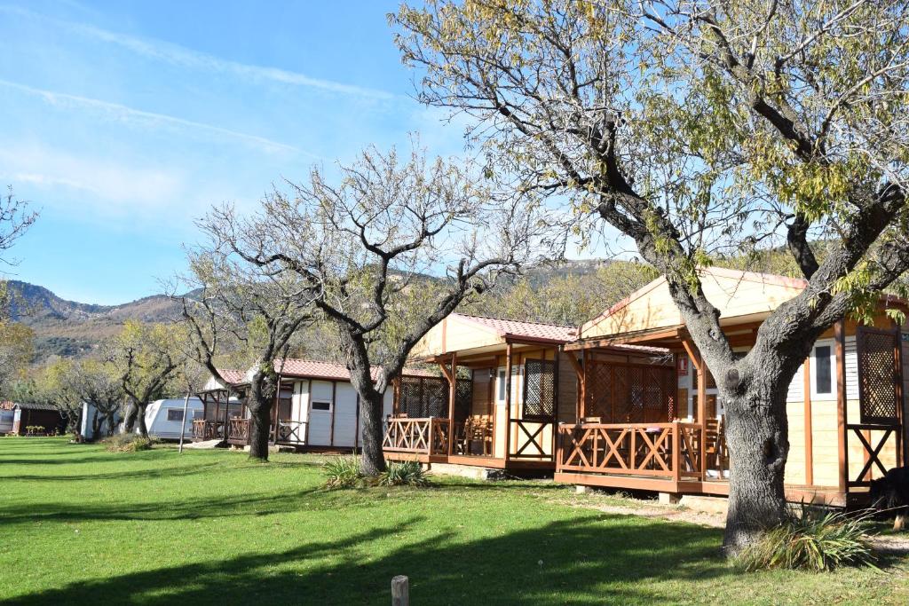 ein großes Holzhaus mit Bäumen im Hof in der Unterkunft Camping Castillo de Loarre in Loarre