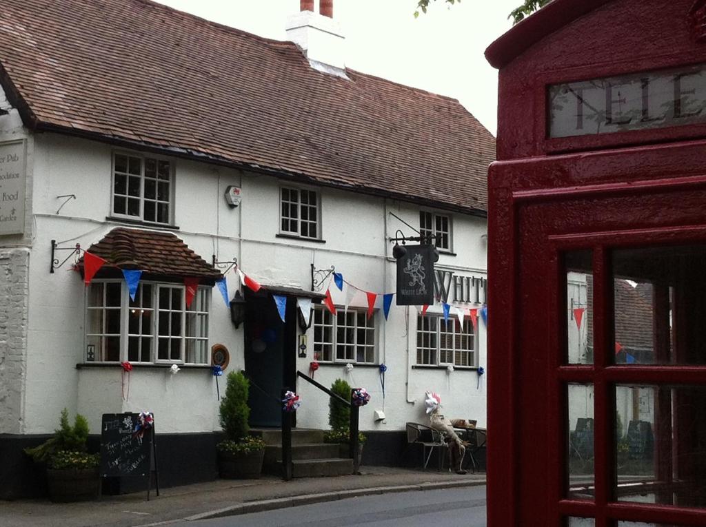 a white building with flags hanging outside of it at The White Lion Inn in Hampton in Arden