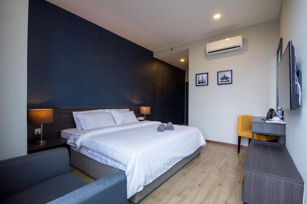 - une chambre avec un grand lit et un canapé dans l'établissement OMG Hotel, à Simpang Ampat