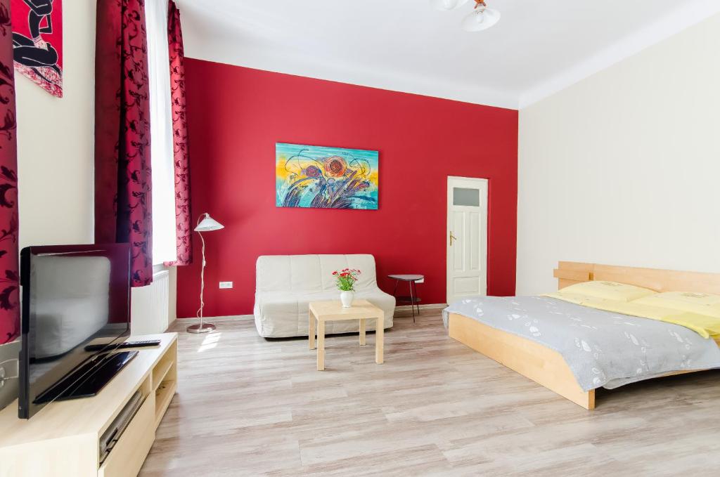 1 dormitorio con pared roja, cama y TV en Fantasia Apartments, en Cracovia