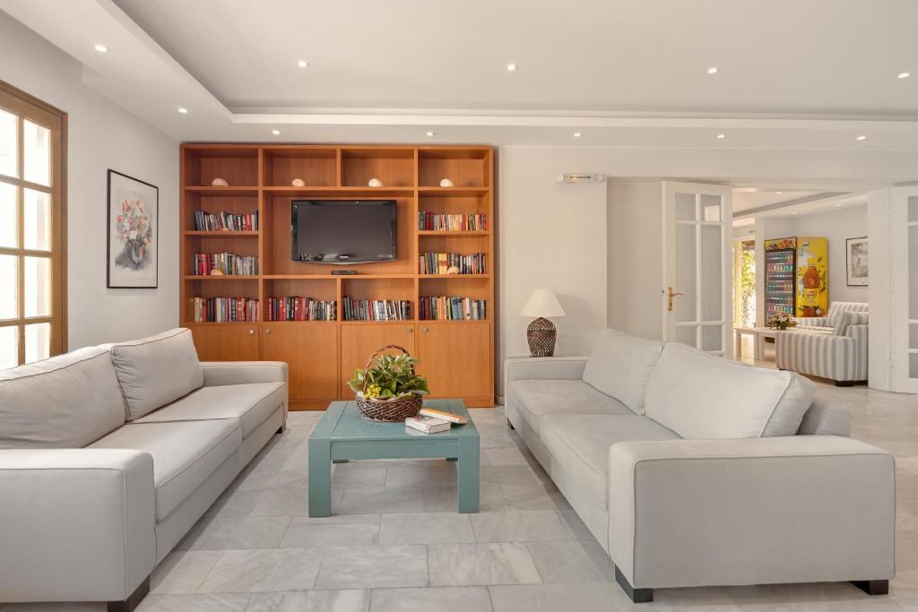 sala de estar con 2 sofás blancos y TV en Mare Hotel Apartments, en Agios Nikolaos