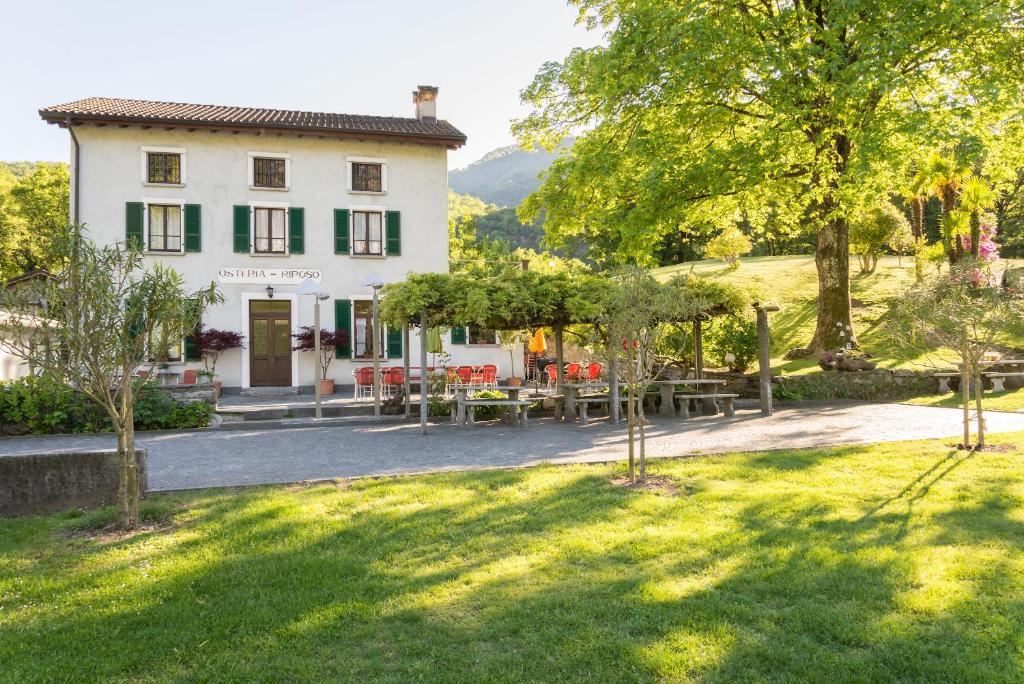 un bâtiment avec des tables et des chaises dans une cour dans l'établissement Ostello & Camping Riposo, à Losone