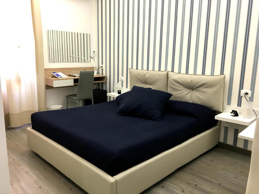 a bedroom with a bed with a blue blanket and a desk at Deluxe B&B Centrocitta in Reggio di Calabria