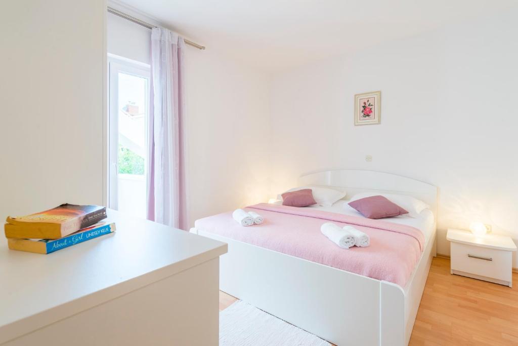 a white bedroom with a bed and a window at Apartments Nikolina in Hvar