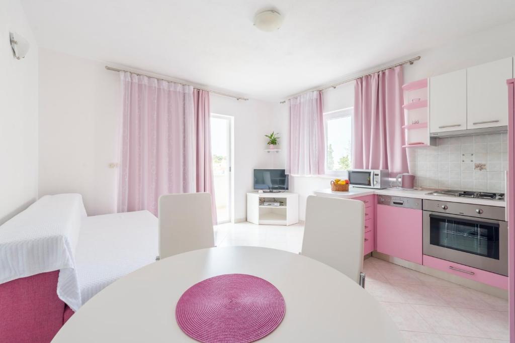a kitchen with a white table and pink cabinets at Apartments Nikolina in Hvar