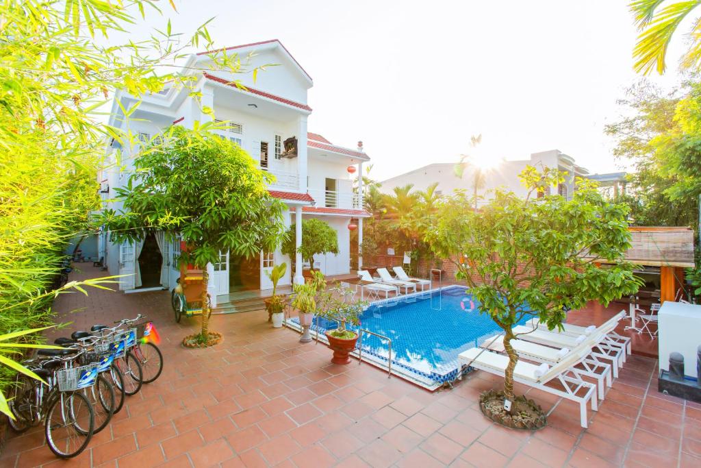 a patio with a pool and chairs and trees at Hoi An Life Villa in Hoi An