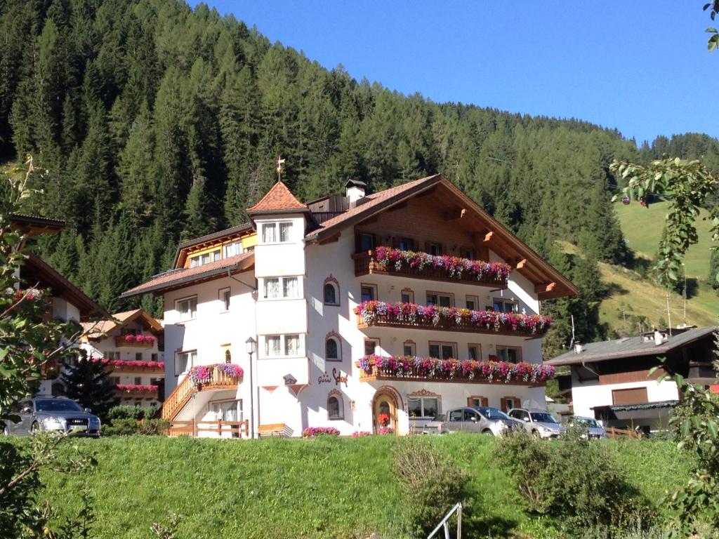 - un grand bâtiment blanc avec des fleurs sur le balcon dans l'établissement Garni Schenk, à Selva di Val Gardena