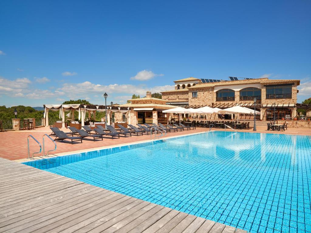 a swimming pool with chairs and a building in the background at Hapimag Resort Mas Nou in Platja  d'Aro