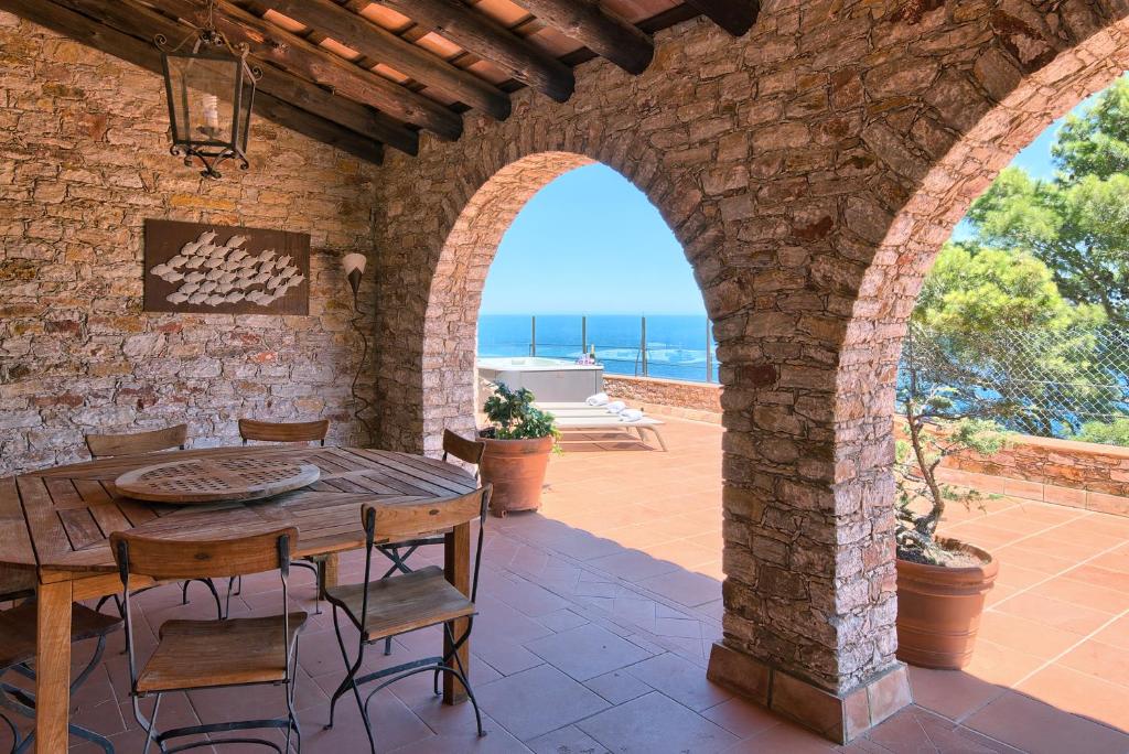 een patio met een houten tafel en stoelen bij Sa Tuna Villa CEMA in Begur
