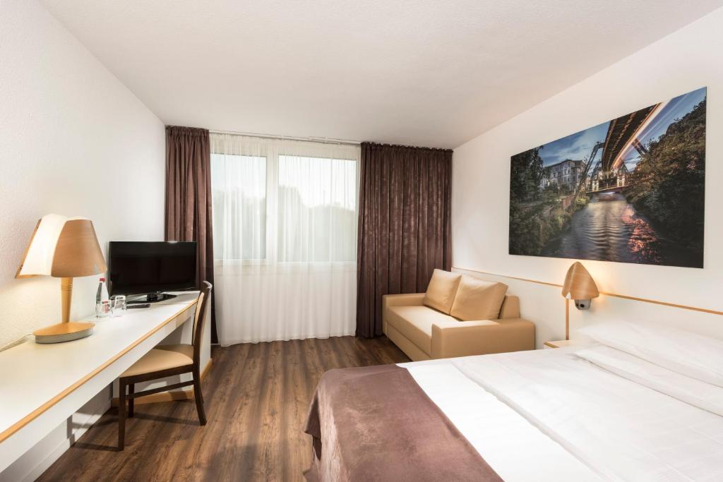 a hotel room with a large bed and a television at Tryp by Wyndham Wuppertal in Wuppertal