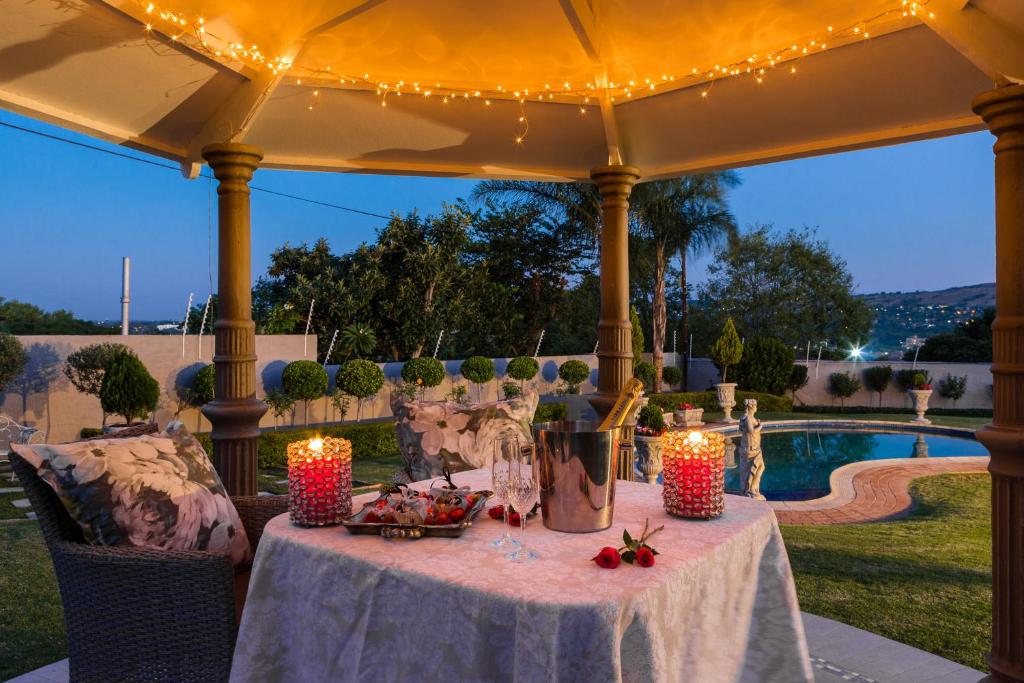 a table under an umbrella with candles and lights at La Vida Luka - Luxury Guesthouse in Pretoria