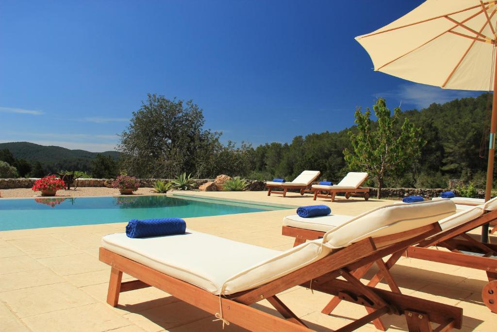 un grupo de sillas y una sombrilla junto a la piscina en Casa Vilda, en Sant Mateu d’Albarca