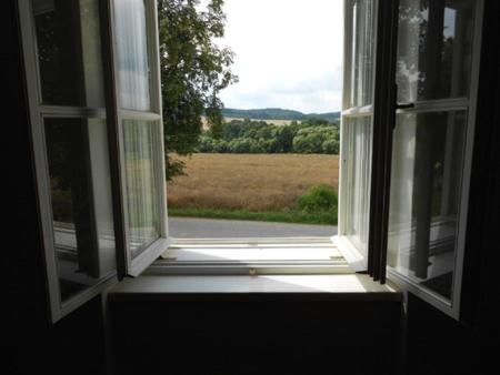 an open window with a view of a field at Zámek Dobrohoř in Dobrohoř