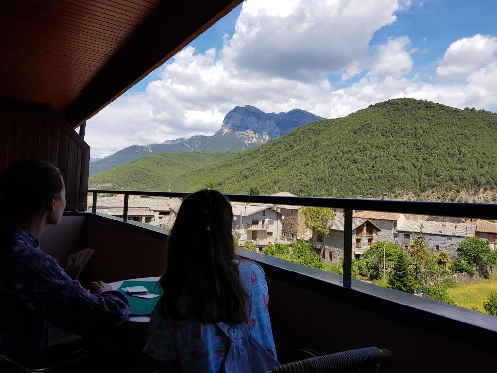 zwei Personen, die aus einem Fenster auf einen Berg blicken in der Unterkunft Apartamentos Turmo in Labuerda