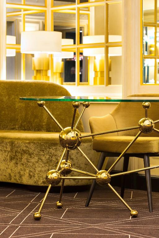 a glass table and a chair next to a couch at Hotel Barsey by Warwick in Brussels