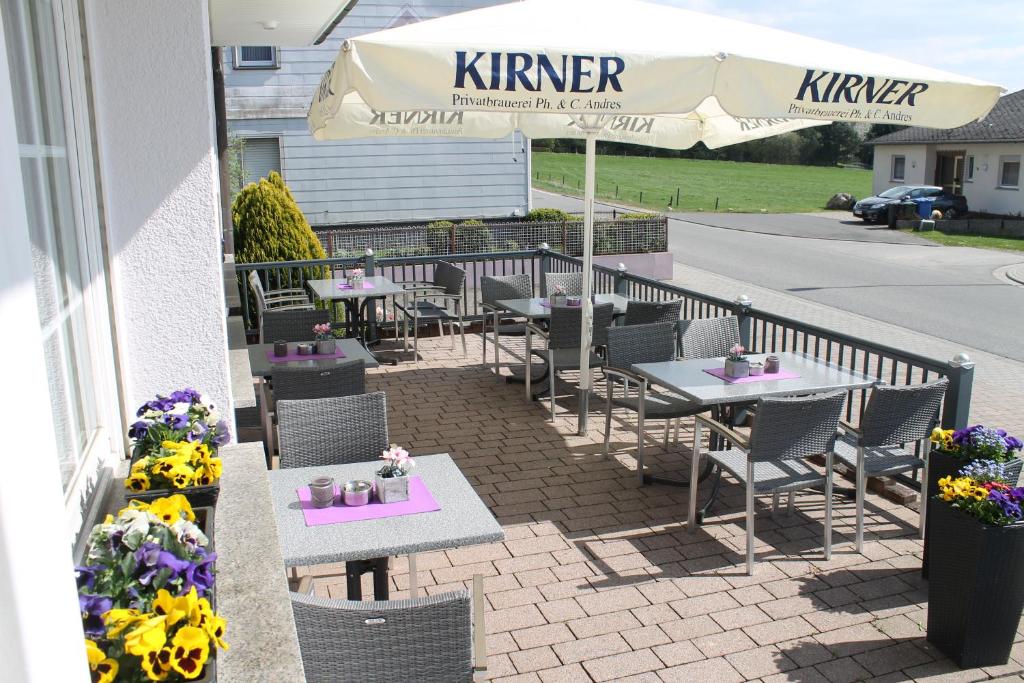 un patio con tavoli, sedie e ombrellone di Hotel Schatulle a Laufersweiler