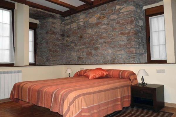 a bedroom with a bed and a stone wall at Eskolazaharra in Oronoz-Mugaire