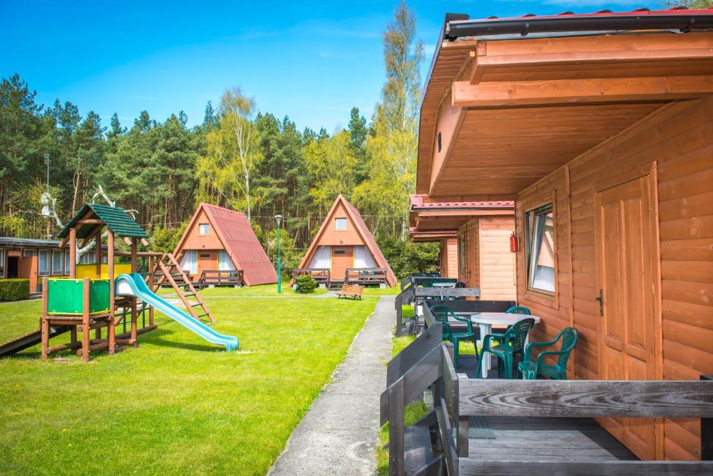 a yard with a playground with a slide and houses at Domki Kempingowe Krzysztof in Łeba