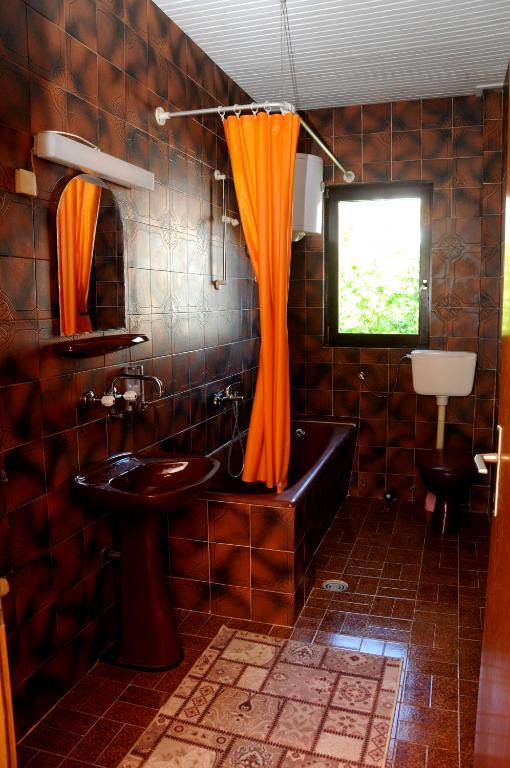 e bagno con tenda doccia arancione e vasca. di Guest House Smajlaga a Ulcinj