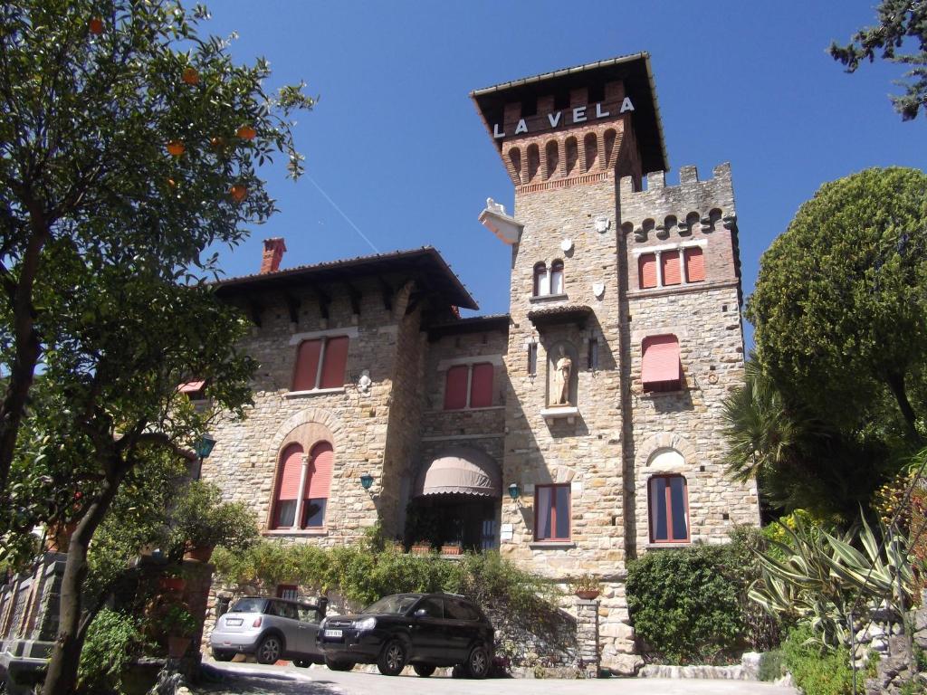 a large stone building with cars parked in front of it at Hotel La Vela-Castello Il Rifugio in Santa Margherita Ligure