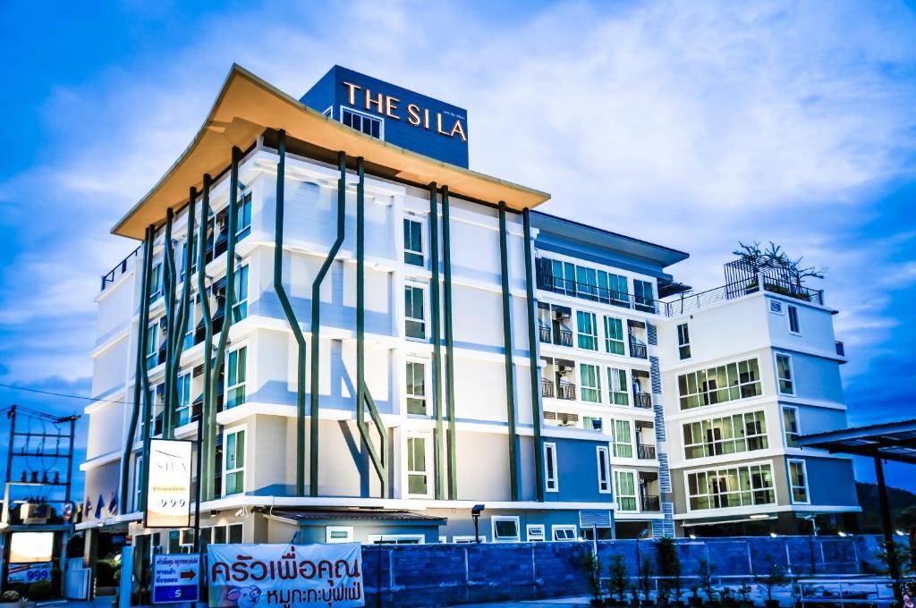 un gran edificio blanco con un cartel azul en The Sila Hotel en Si Racha